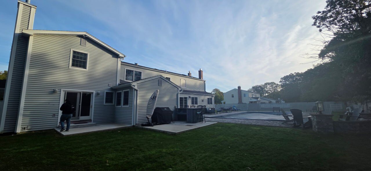 Rear of a two-story home with patio and pool, with an instructor at the slider door during a mock inspection