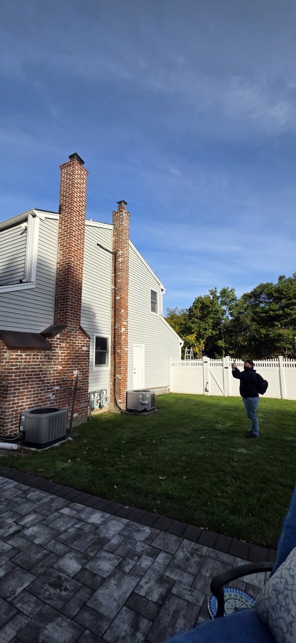 Side of a house with brick chimney and AC condenser